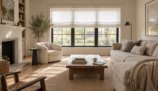 Modern farmhouse living room with a white relaxed roman blind, painted fireplace and bouclé armchair